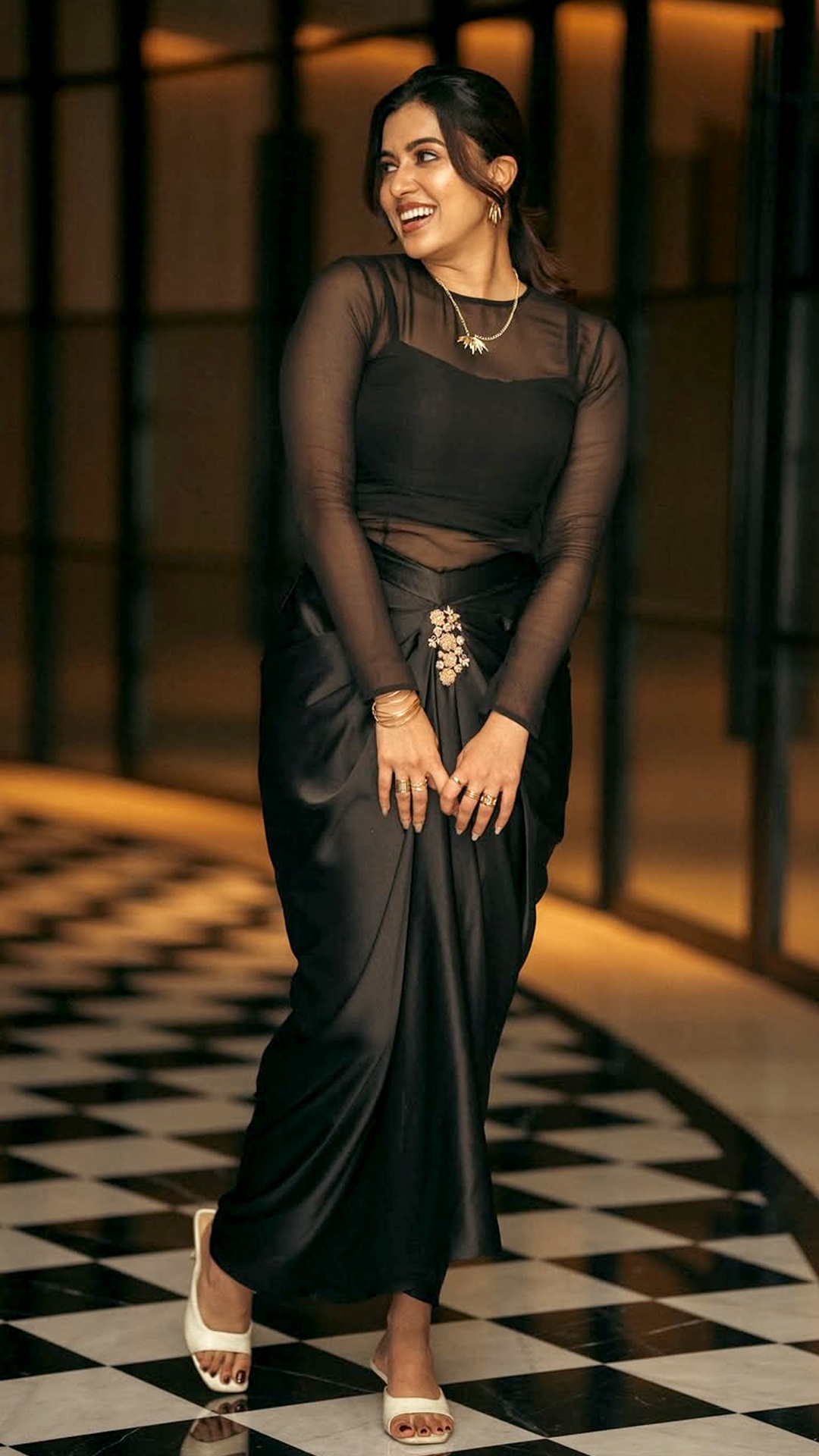 Anju Kurian's Recent Photoshoot - She turns heads in a monochrome black ensemble featuring a sheer mesh top and a stylishly draped satin skirt, accessorized with statement gold jewels.