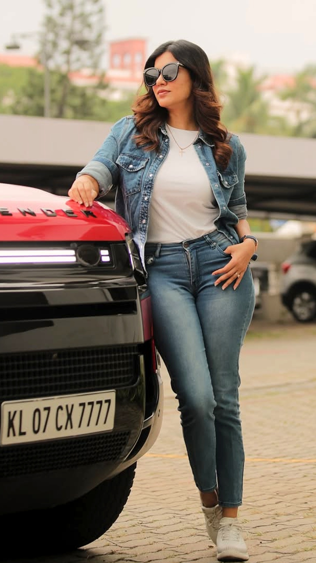 Anju Kurian's Recent Photoshoot - She rocks a classic denim-on-denim vibe with a structured jacket and fitted jeans, perfectly complementing the rugged luxury of the Defender.