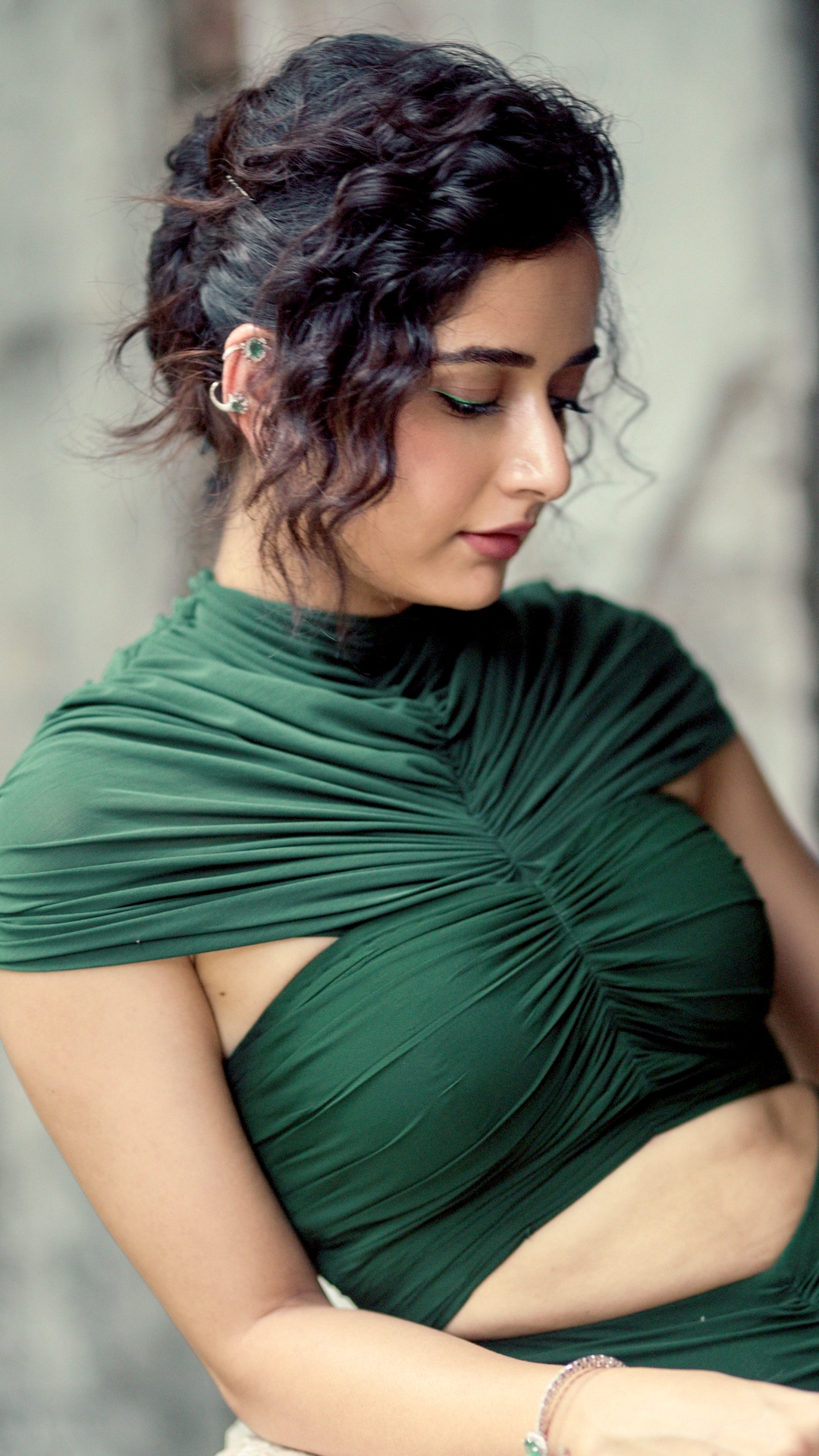 Ashika Ranganath's Recent Photoshoot - Vertical ruching gathers at the centre front, drawing the eye downward to a sharp diamond-shaped cutout at the waist.