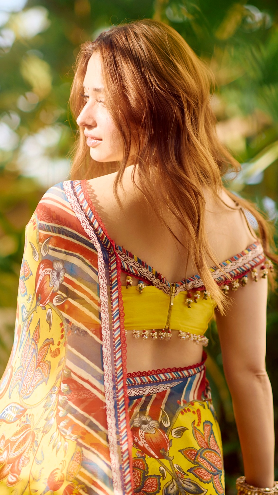 Tamannaah Bhatia's Recent Photoshoot - Turn around, and the blouse reveals a deep V-shaped back closed with a zipper, finished with strings of colourful beads along the edge.