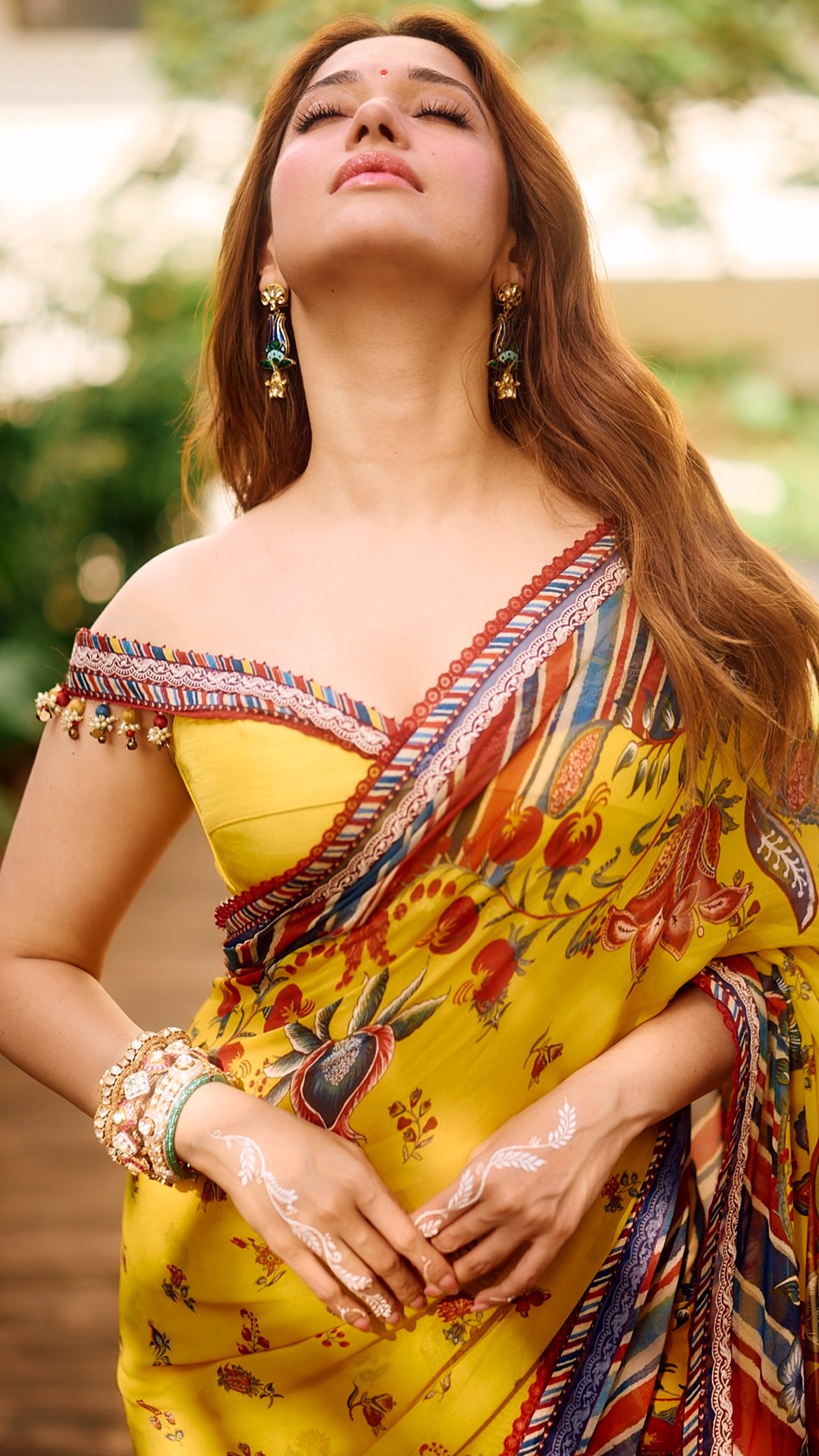 Tamannaah Bhatia's Recent Photoshoot - The bright yellow blouse falls off the shoulder, echoing the saree's striped border right along its neckline.