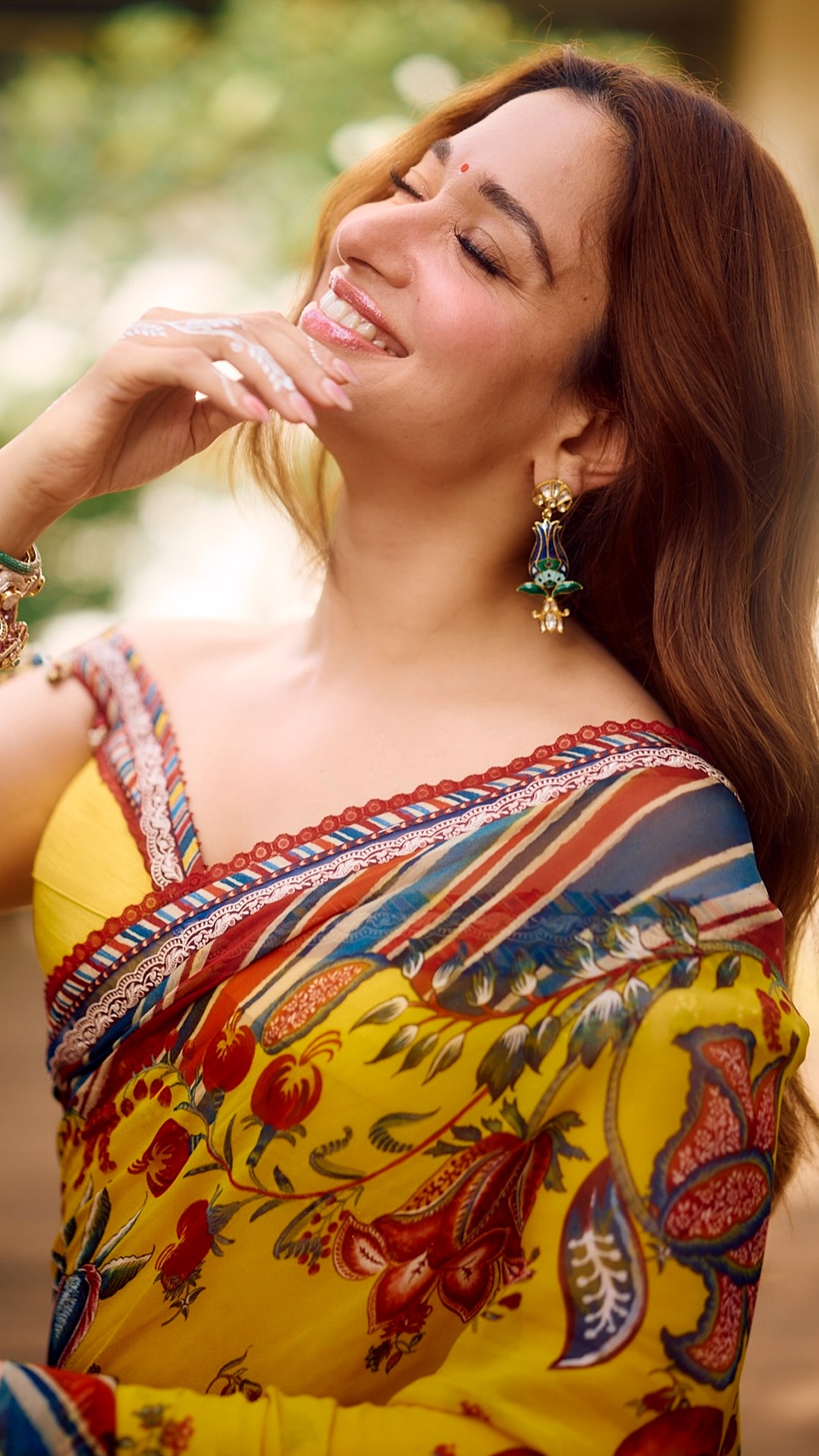 Tamannaah Bhatia's Recent Photoshoot - Torani's yellow saree carries a dense floral print, framed by a striped, multicolour border running along its edge.